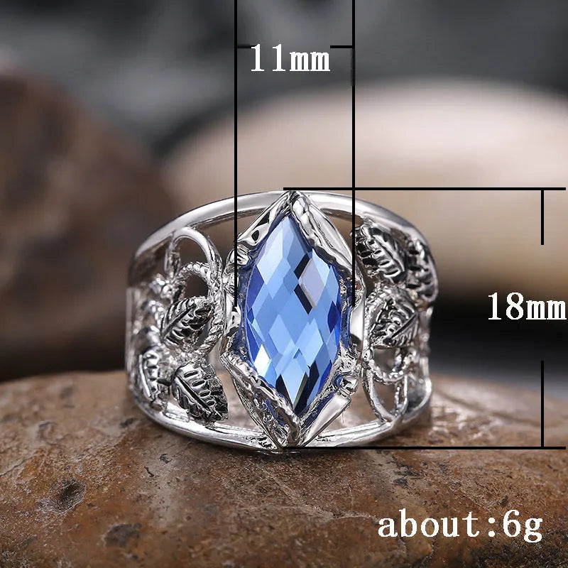Close-up of a blue crystal horse eye-shaped geometric alloy ring on a person's finger.