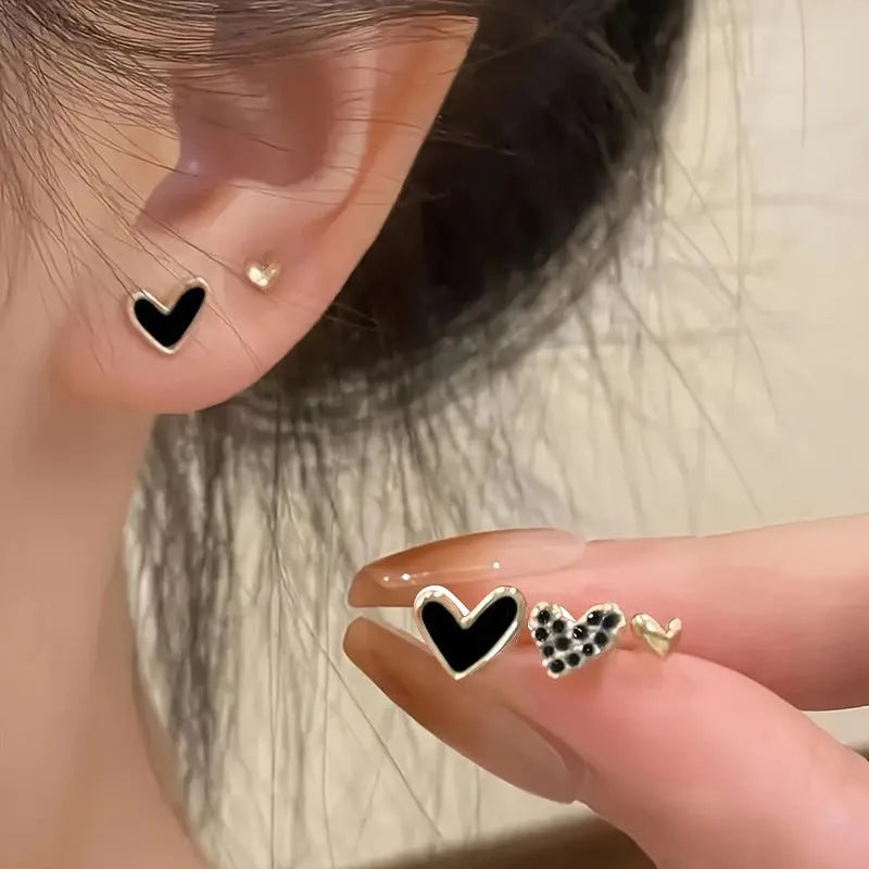 Set of three pairs of women's heart-shaped alloy drop earrings in gold, black, pink colours.