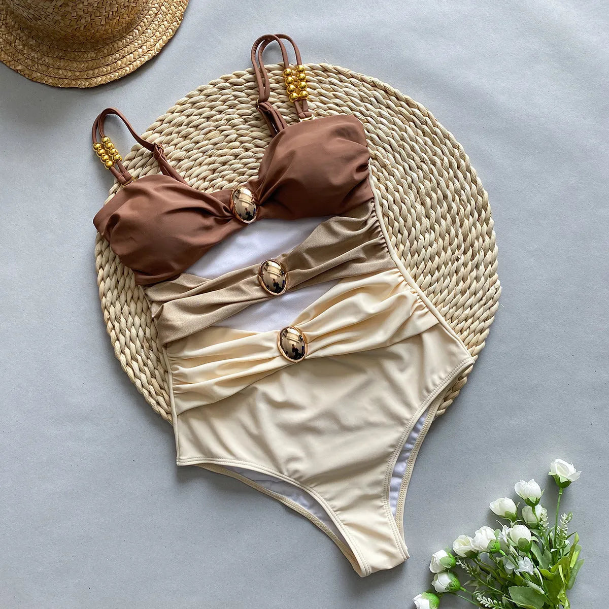 Women's brown one-piece swimsuit with matching beige skirt laid flat