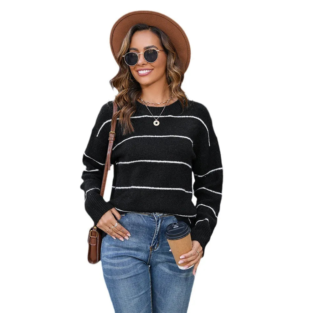 A woman wearing a black and white striped, loose-fit polyester pullover sweater with a round neck.