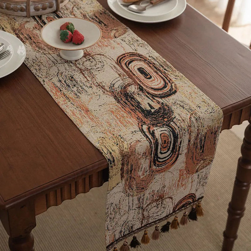 Dark blue and white striped jacquard table runner with tassel trim laid on a wooden dining table.