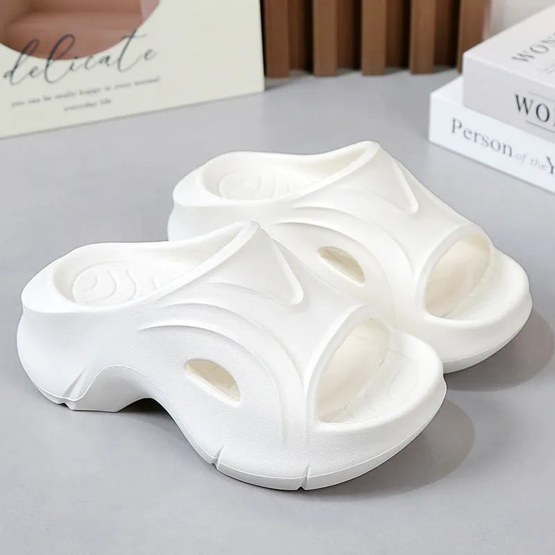 Women's white thick-soled EVA slippers with rounded toe on a sandy beach.