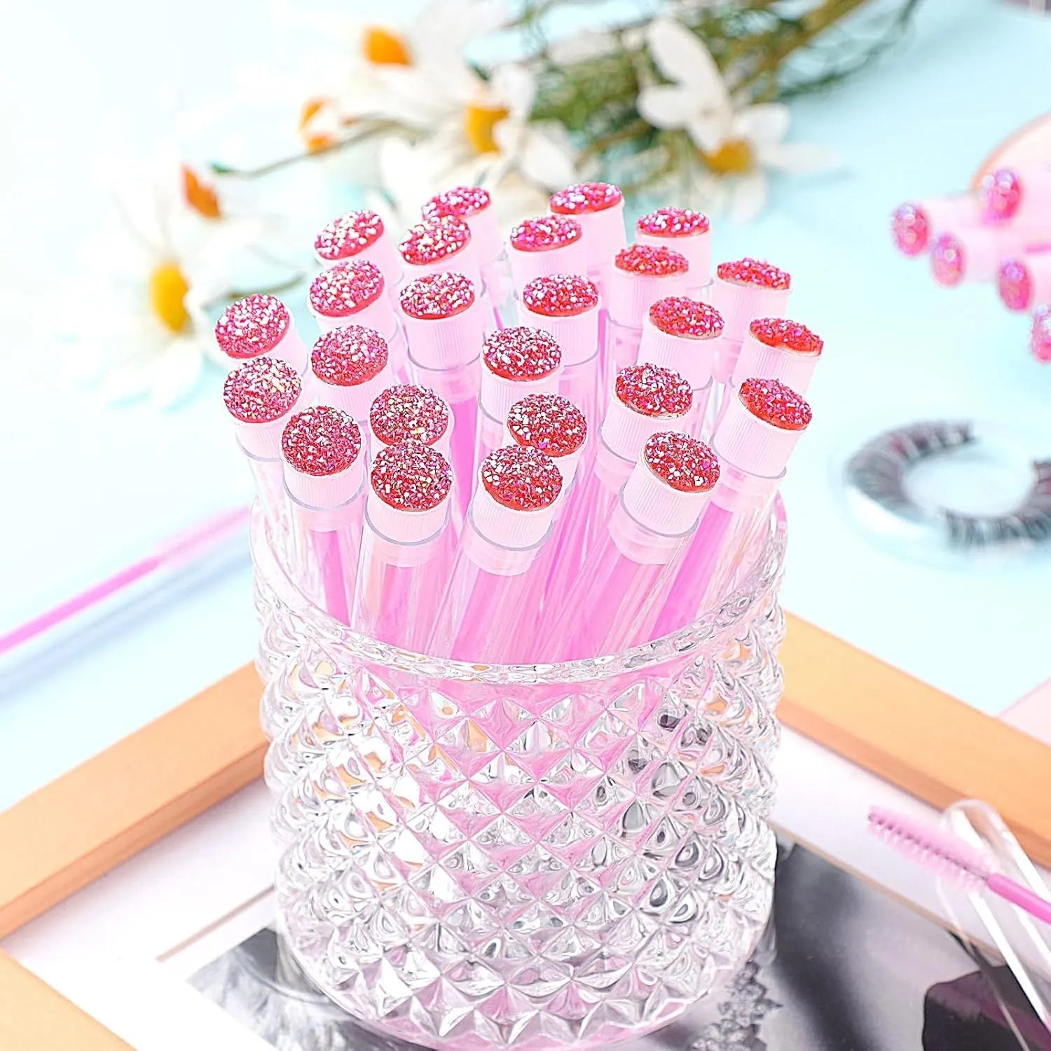 Set of coloured disposable eyelash spoolie brushes inside clear plastic storage tubes.
