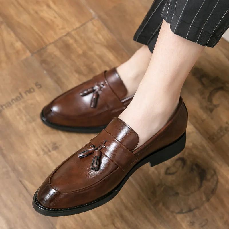 Men's black slip-on business casual shoes with a tassel detail and rubber sole.