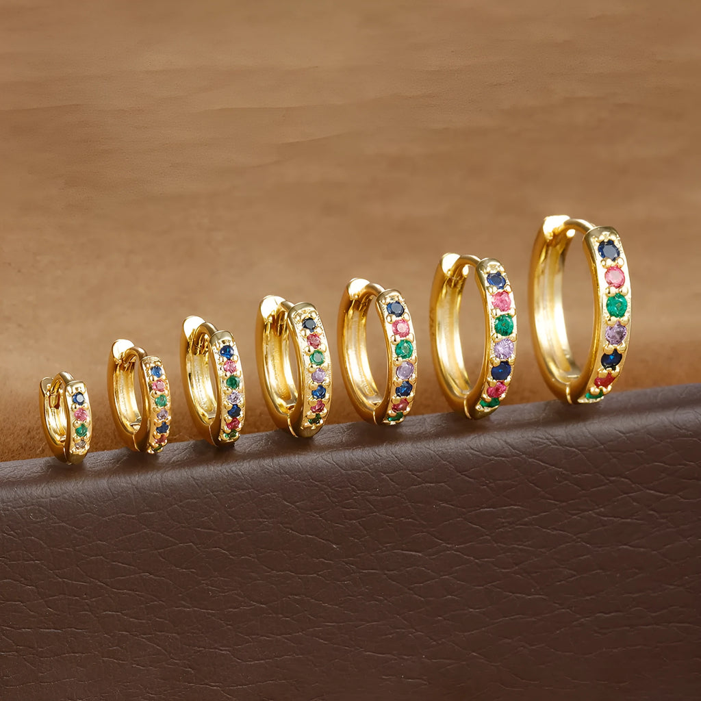 A pair of round gold-coloured stud earrings with a geometric perforated design and central zircon stone.