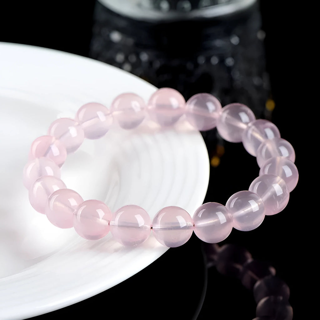 Close-up of a polished natural starlight crystal round bead bracelet in pink, showing single circle design.