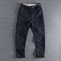 Men's khaki cotton work trousers with N I buckle belt and three-dimensional cut on a hanger.