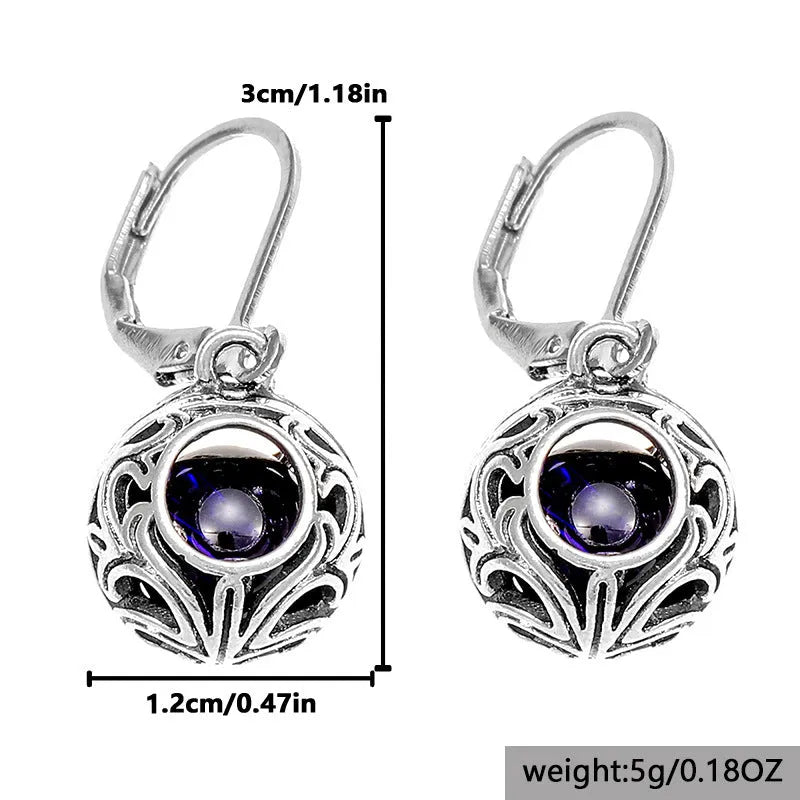 Silver tone pendant earrings with hollow geometric design, blue gemstones, and vintage engraving detail