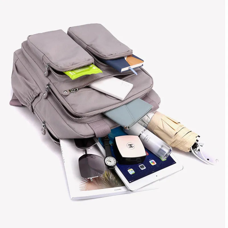 Waterproof women's large capacity nylon travel backpack in multiple colours showing internal laptop compartment and pockets.