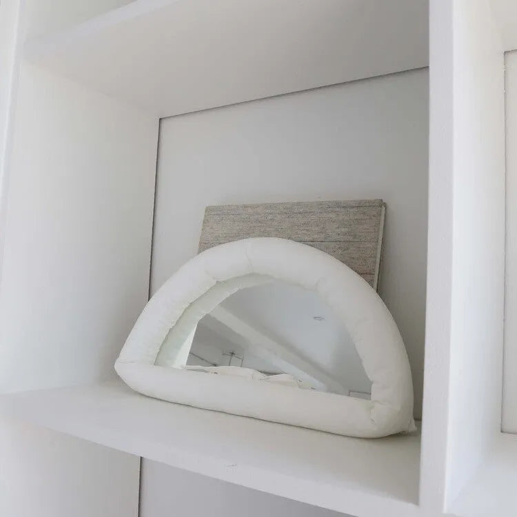 Rectangular white fabric mirror with soft filling hanging on a wall