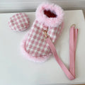 Pink cat wearing a beret and a cloak with a hand holding rope attached.