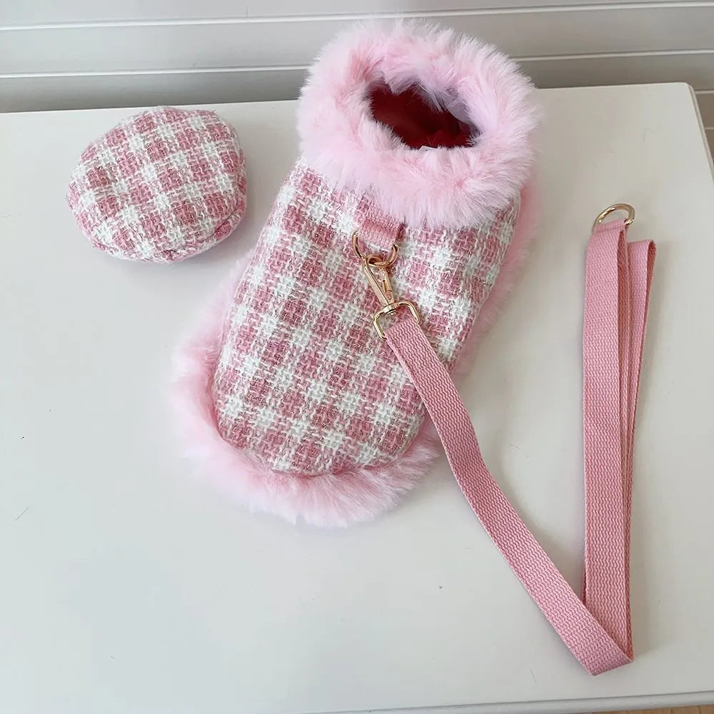 Pink cat wearing a beret and a cloak with a hand holding rope attached.