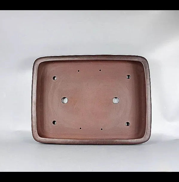 Handmade rectangular purple clay flower pot for indoor plants on a table.