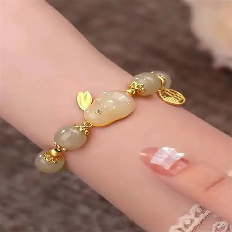 Women's black bracelet with green jade hare charm, fu character, and lily motif detail.
