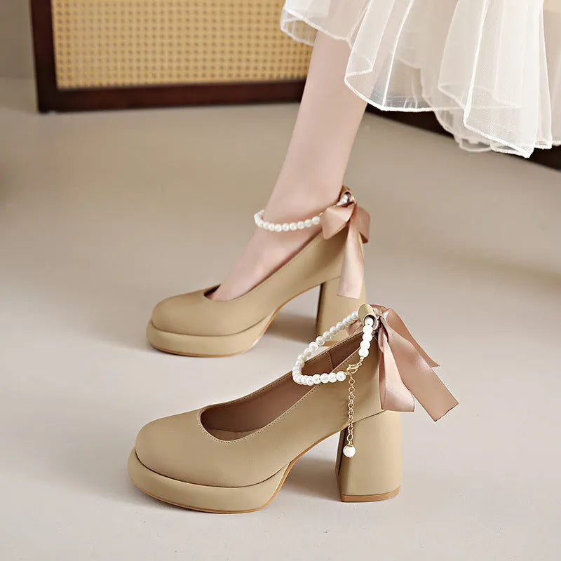Beige women's Mary Jane shoes with a chunky heel, round toe, and ankle strap with a pearl and buckle.