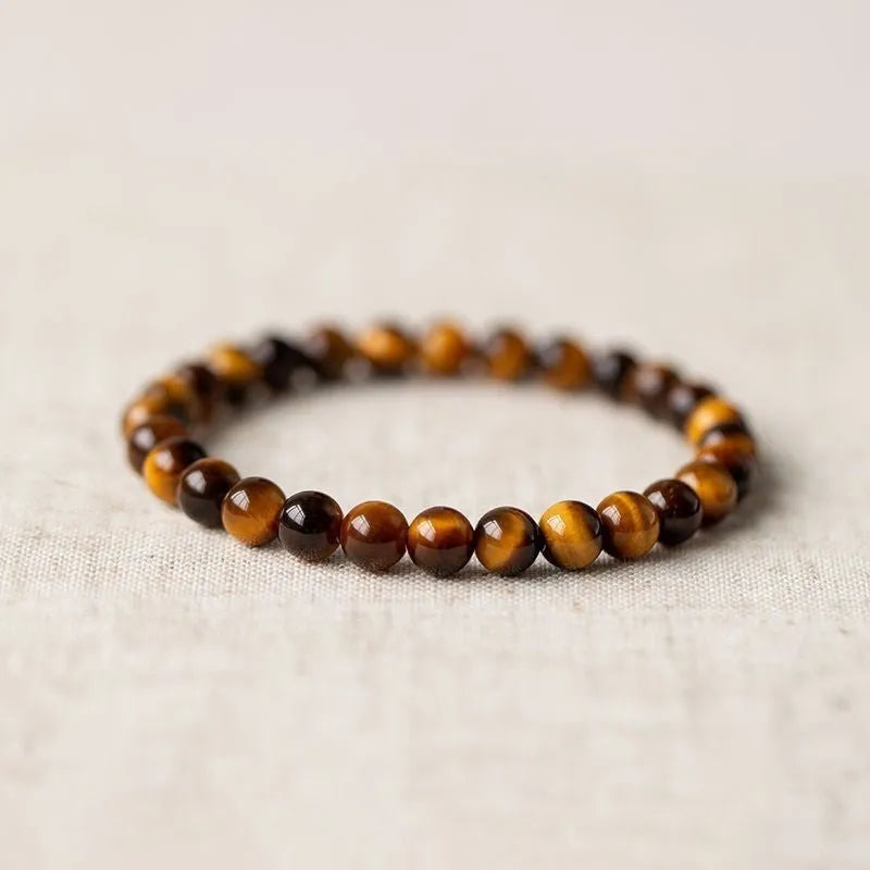 Single circle tigereye stone Buddhist prayer beads bracelet on wrist, showing ethnic design.