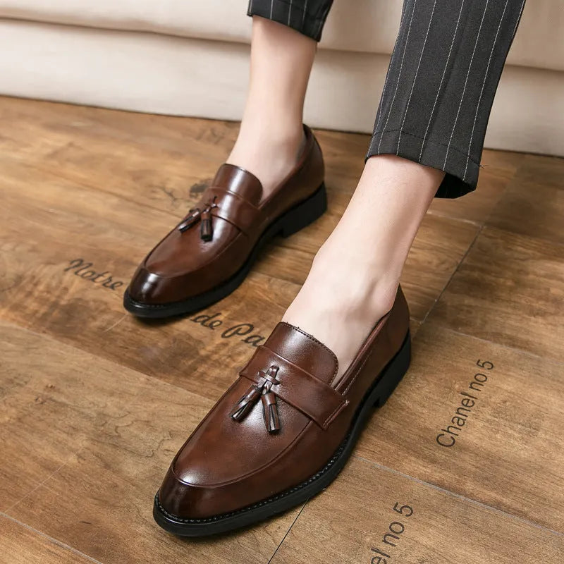 Men's black slip-on business casual shoes with a tassel detail and rubber sole.