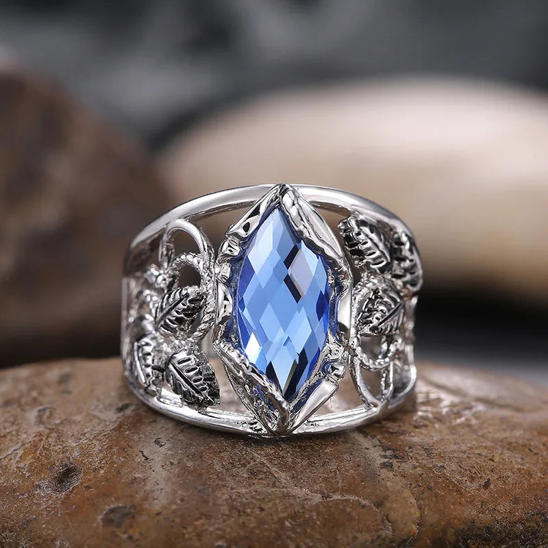 Close-up of a blue crystal horse eye-shaped geometric alloy ring on a person's finger.