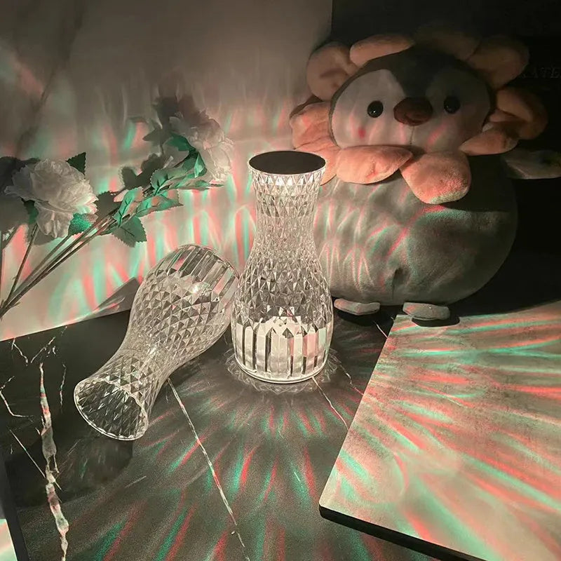 Clear plastic vase-shaped crystal bedside lamp with LED lights on a wooden table.