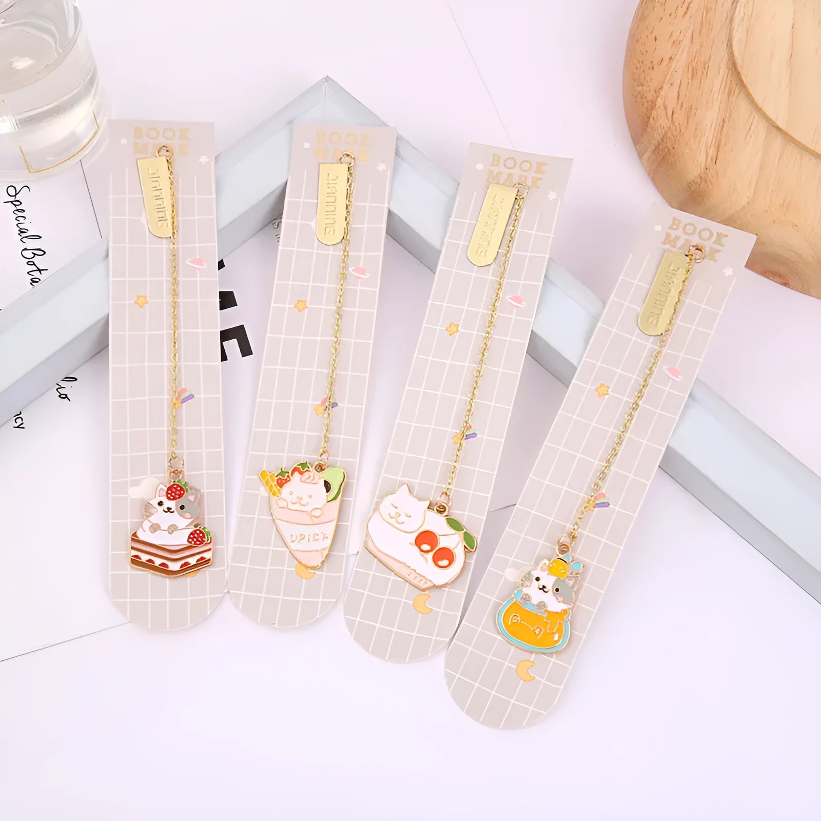 Metal cartoon cat bookmark with food-themed designs including strawberry cake and fruit roll styles