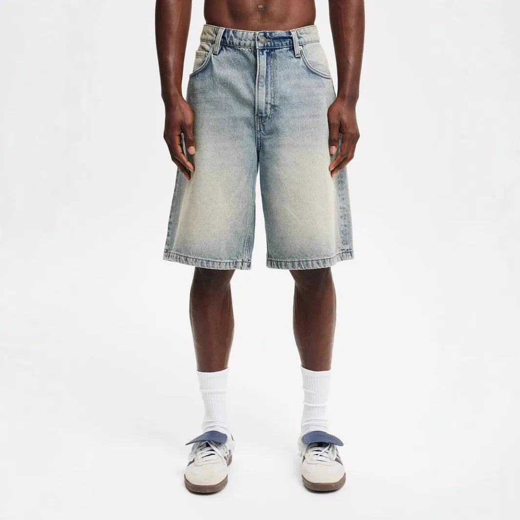 Men's loose straight leg jeans in light blue denim on a plain background
