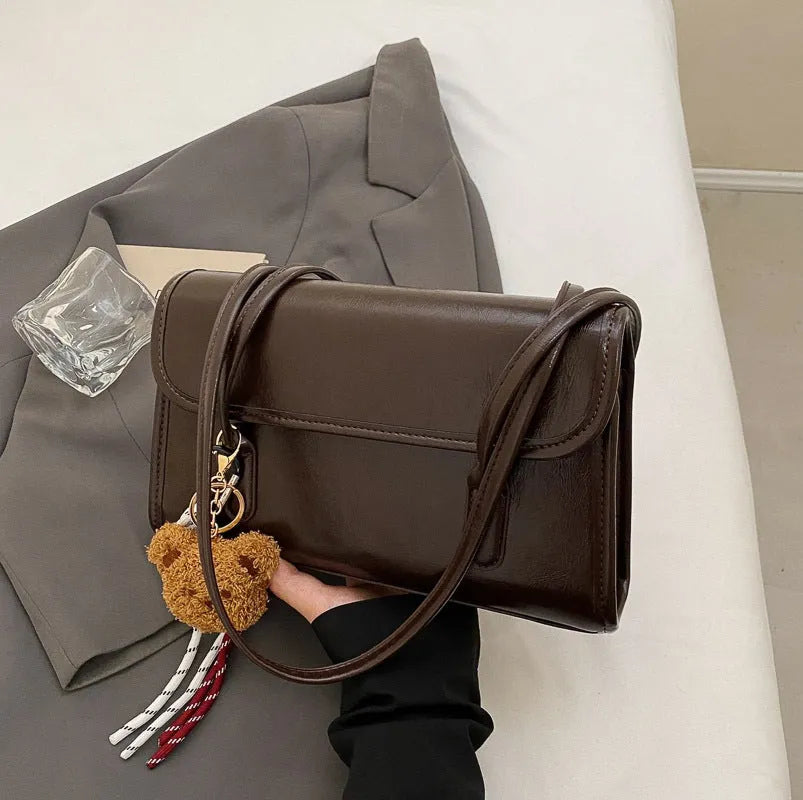 Brown women's PU leather shoulder bag with a square shape, double straps, and a detachable pendant.