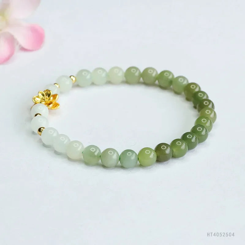 Hand-woven clear water gradient Hetian jade bracelet with flower-shaped beads on a white background.