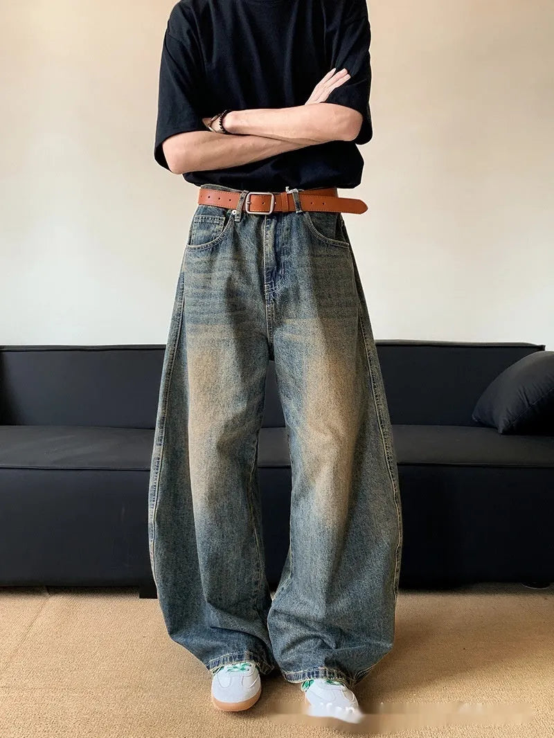 Man wearing retro blue distressed wide-leg denim trousers with a slimming fit.