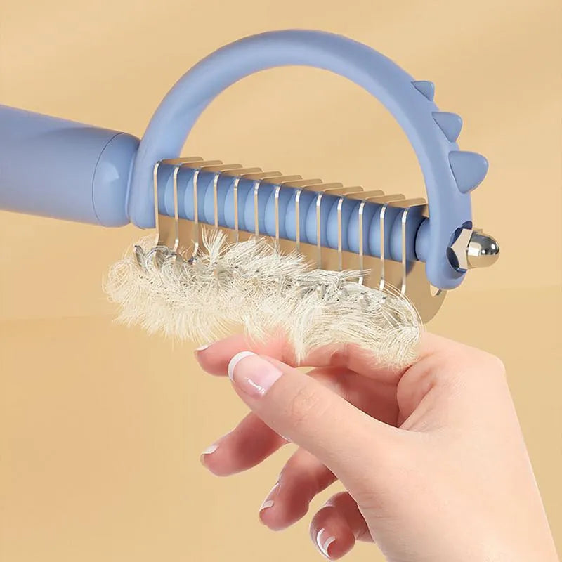 Dinosaur-shaped self-cleaning cat brush with stainless steel bristles in blue, green or white