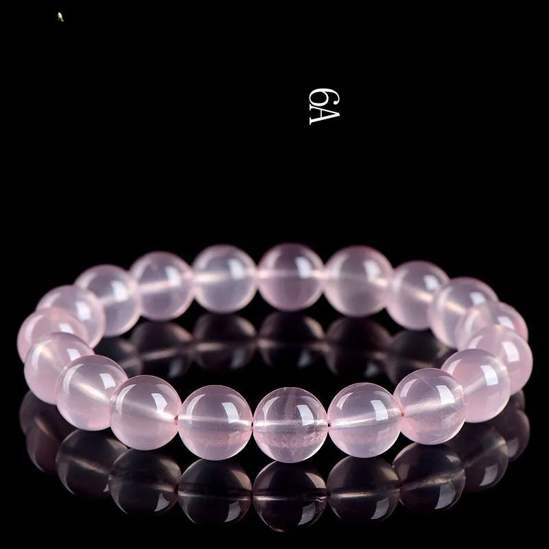 Close-up of a polished natural starlight crystal round bead bracelet in pink, showing single circle design.