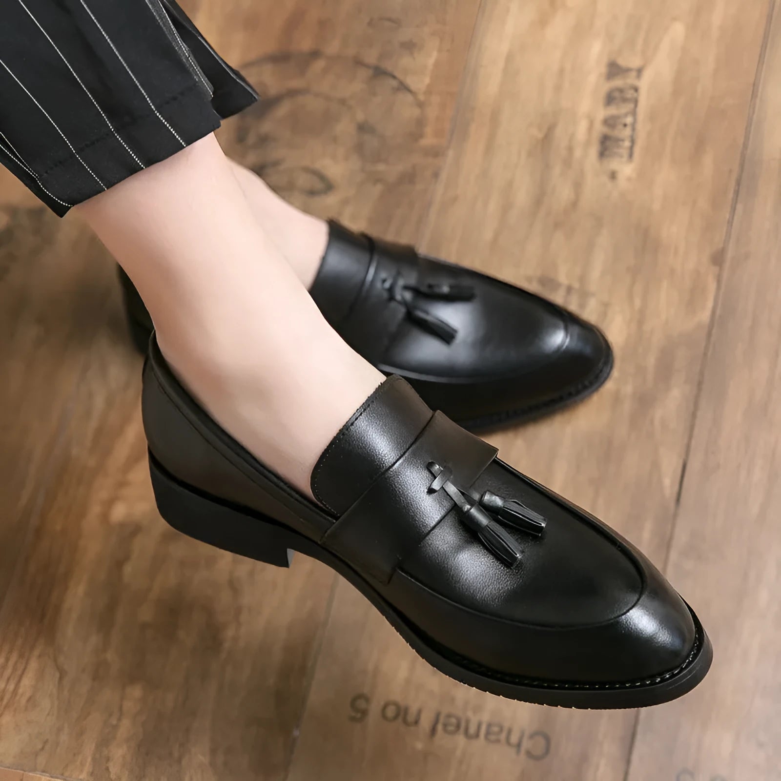 Men's black slip-on business casual shoes with a tassel detail and rubber sole.