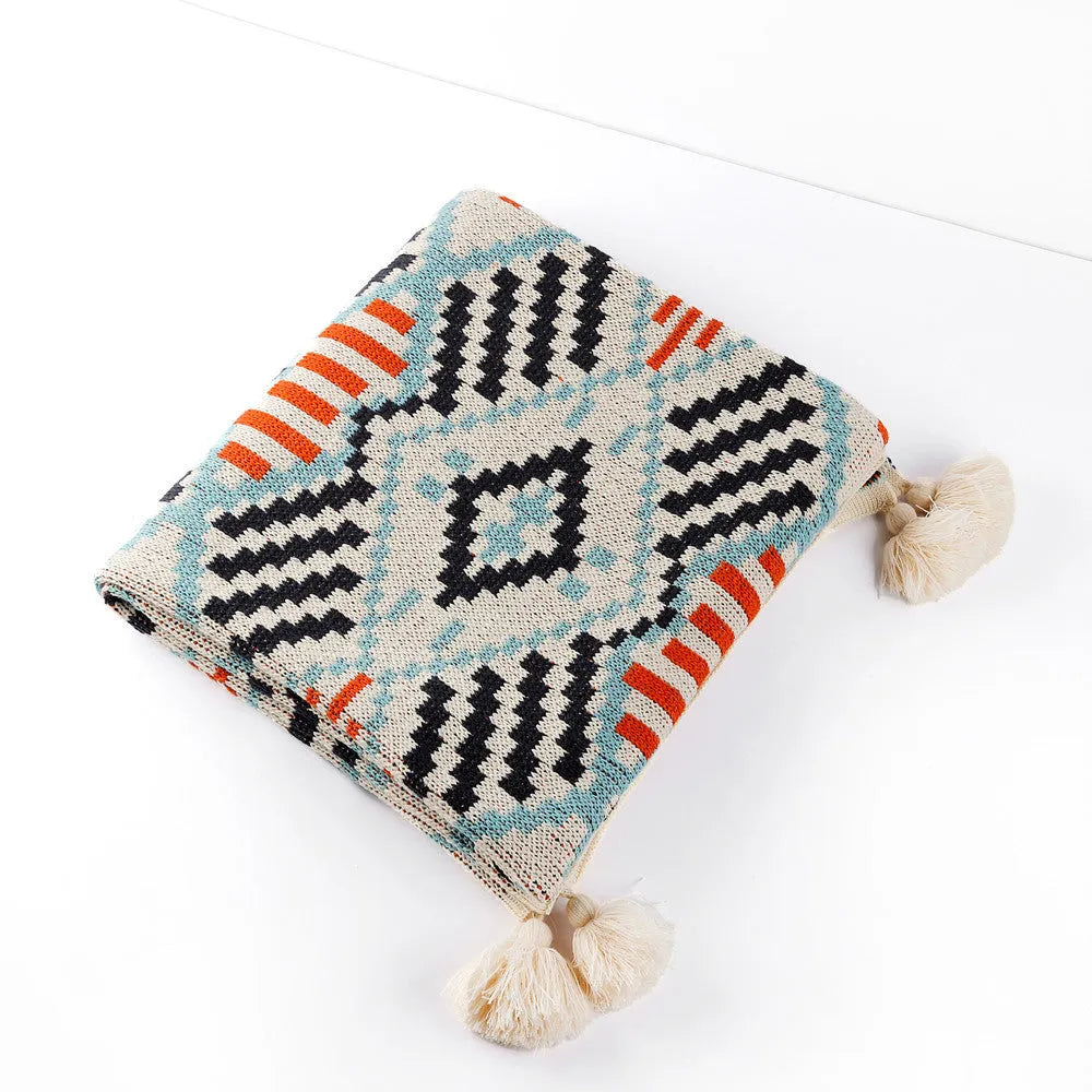 Acrylic sofa blanket with tassels in geometric pattern colour option on a sofa