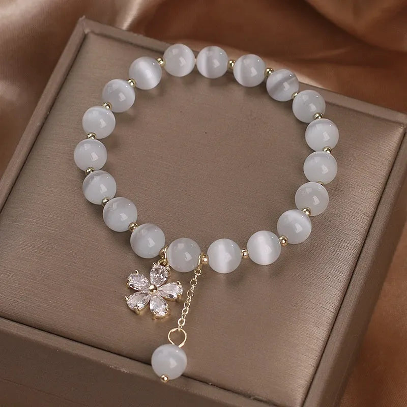 White cat's eye crystal bracelet with a silver flower tassel and safety buckle.