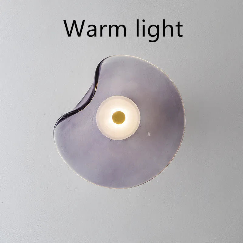 Round glass wall lamp in a choice of colours for bedroom bedside lighting.