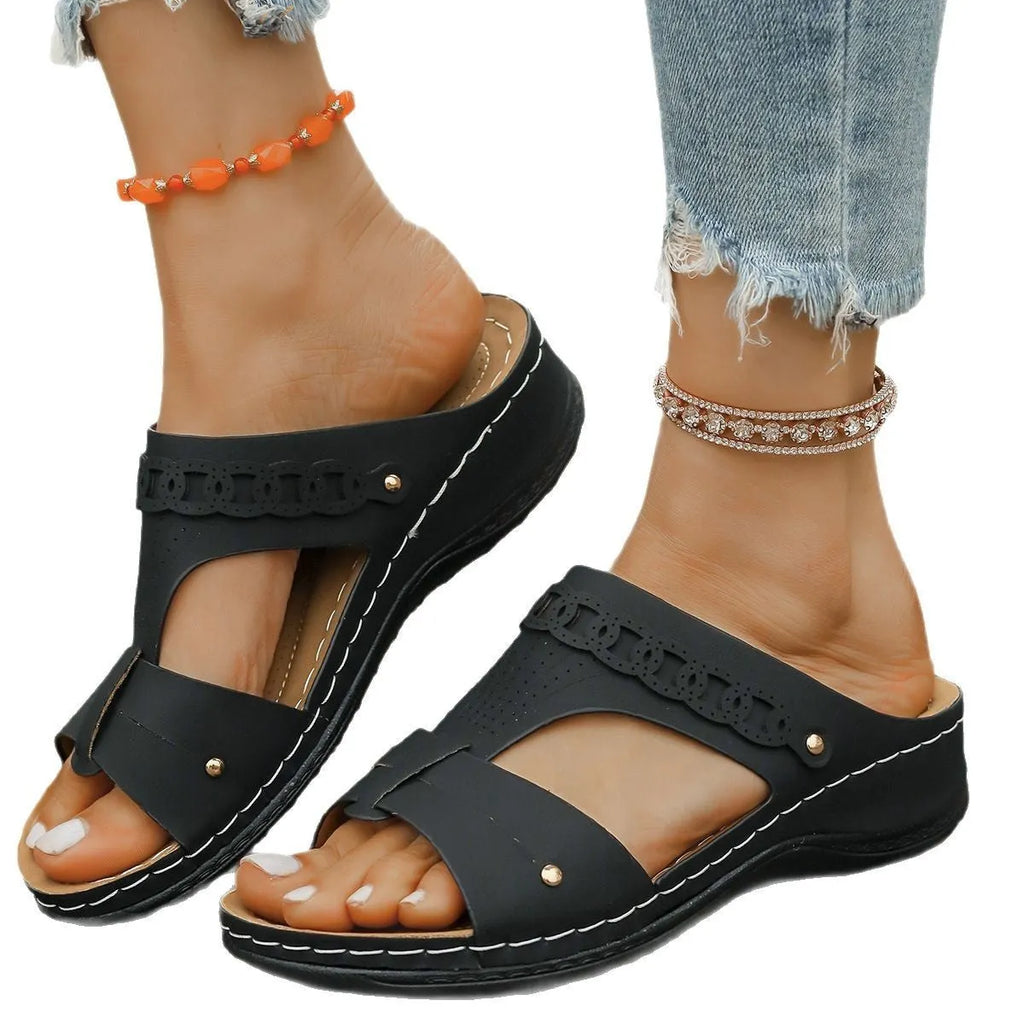 A pair of beige Roman-style slope heel slippers with a fish mouth toe holder on a plain background.