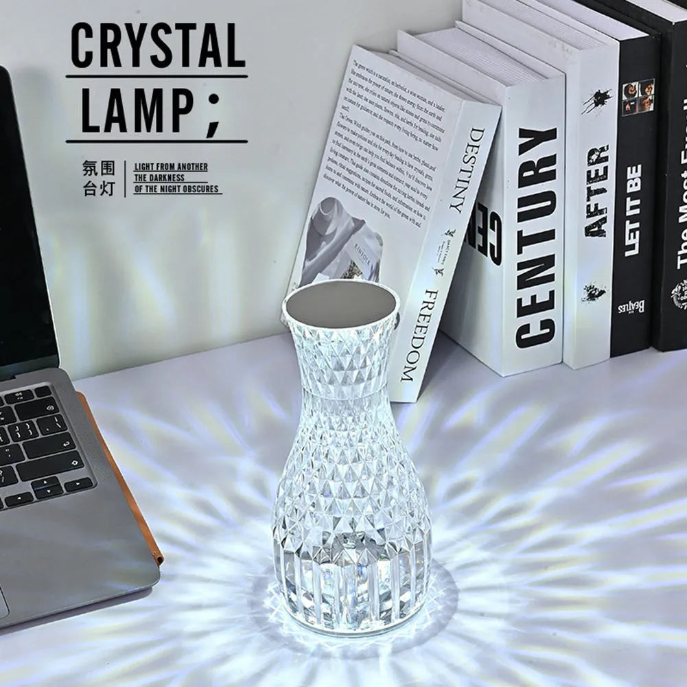Clear plastic vase-shaped crystal bedside lamp with LED lights on a wooden table.