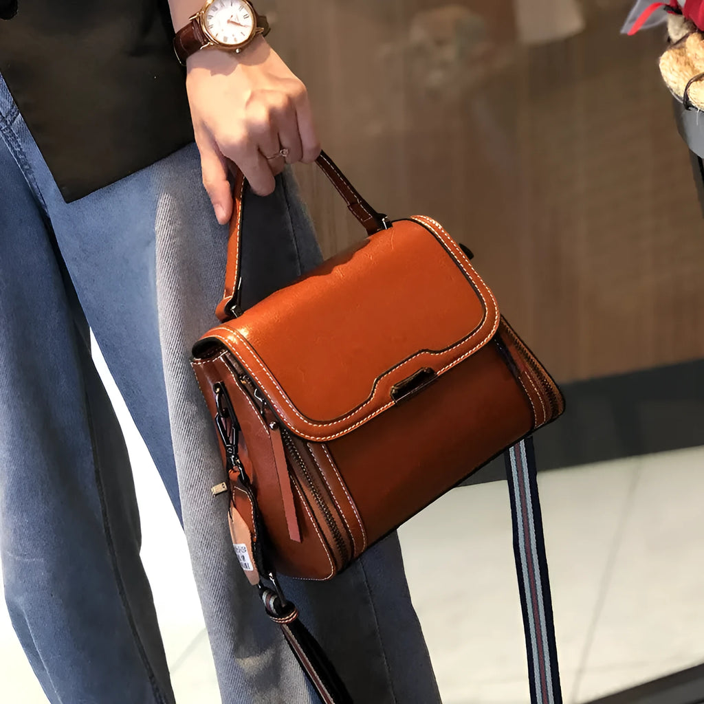 Women's brown genuine oil wax leather messenger bag showing front view with double straps and visible sewing details.