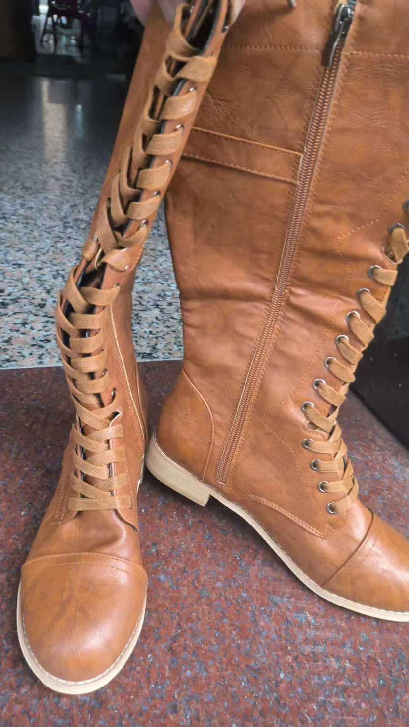 Women's black artificial PU knight boots with cross straps and buckle fastenings.