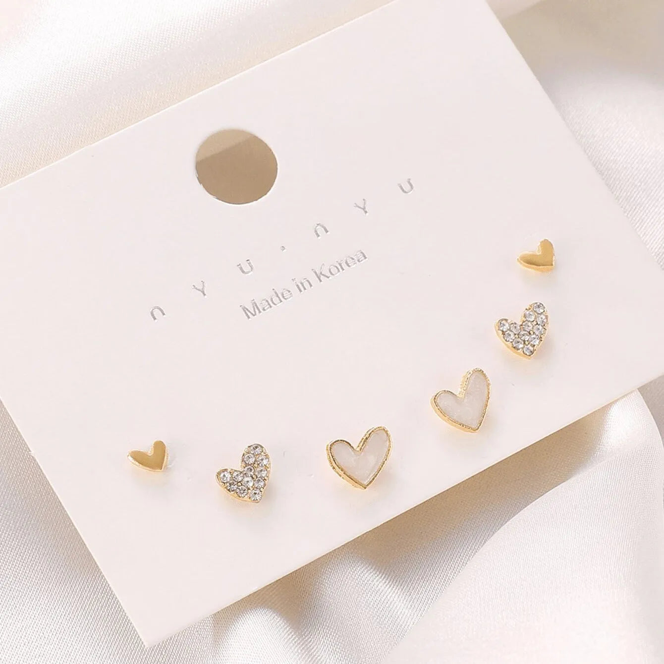 Set of three pairs of women's heart-shaped alloy drop earrings in gold, black, pink colours.