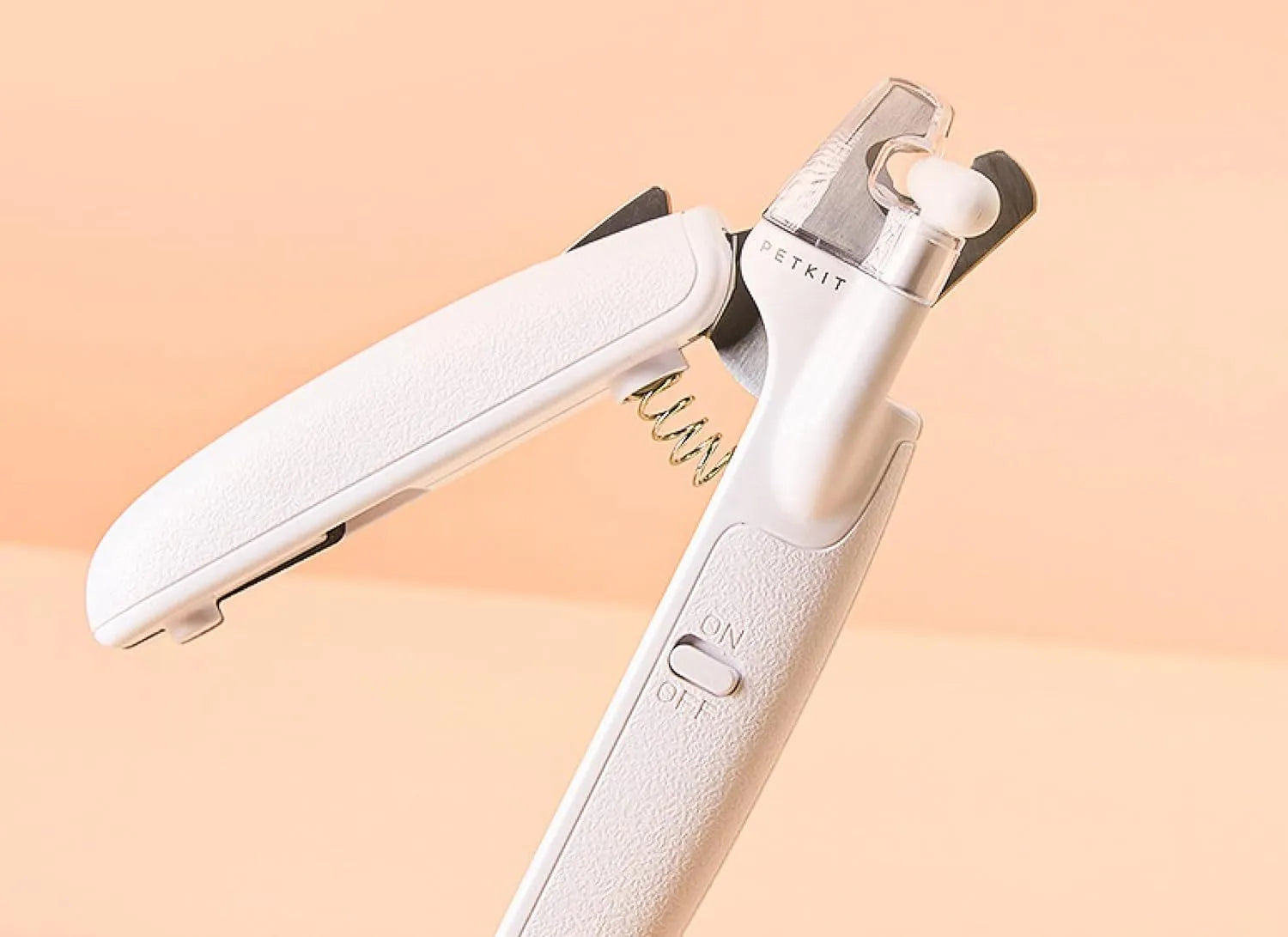 White pet nail clippers with LED light, anti-splash guard, and a nail file on a table.