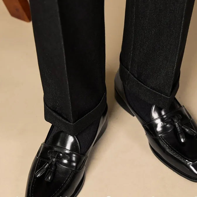 Men's black polished leather tassel loafers on a white background