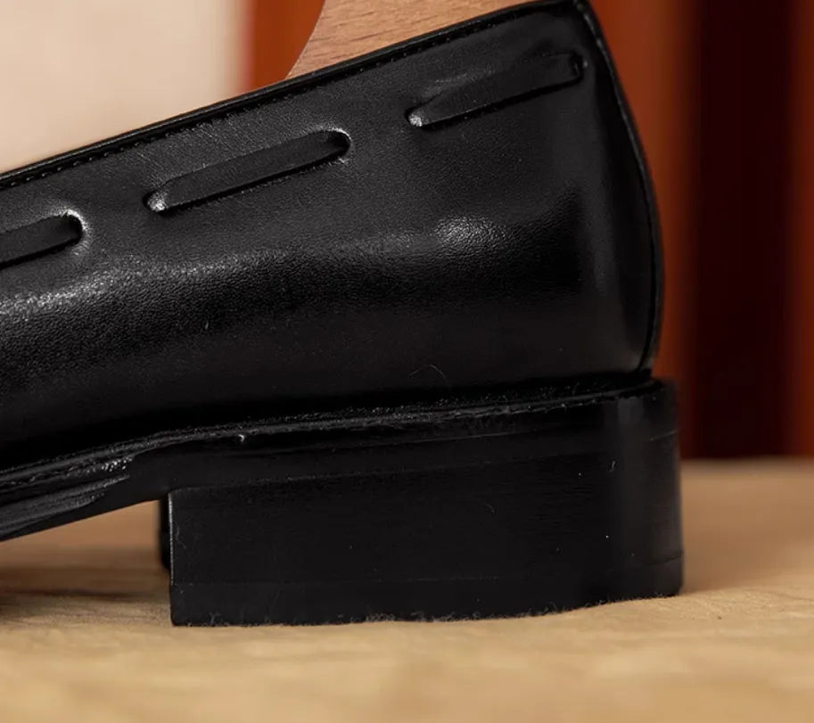 Men's black and brown British-style leather slip-on loafers showing polished leather upper and rubber sole