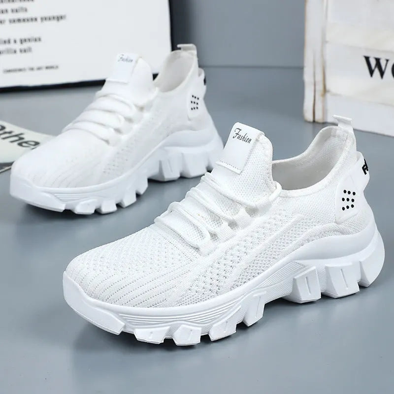 Women's white flyknit casual sneakers with thick PVC sole and round toe, showing lace-up front.