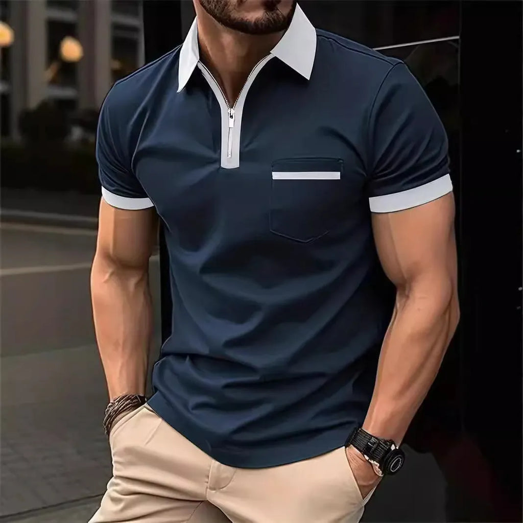 Man wearing a grey and navy blue casual t-shirt with a chest pocket and silver zip decoration detail.