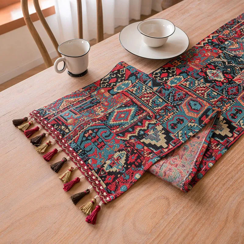 Dark blue and white striped jacquard table runner with tassel trim laid on a wooden dining table.