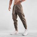 Men's loose fit cotton trousers with ankle-tied cuffs and multiple pockets in a light grey colour.