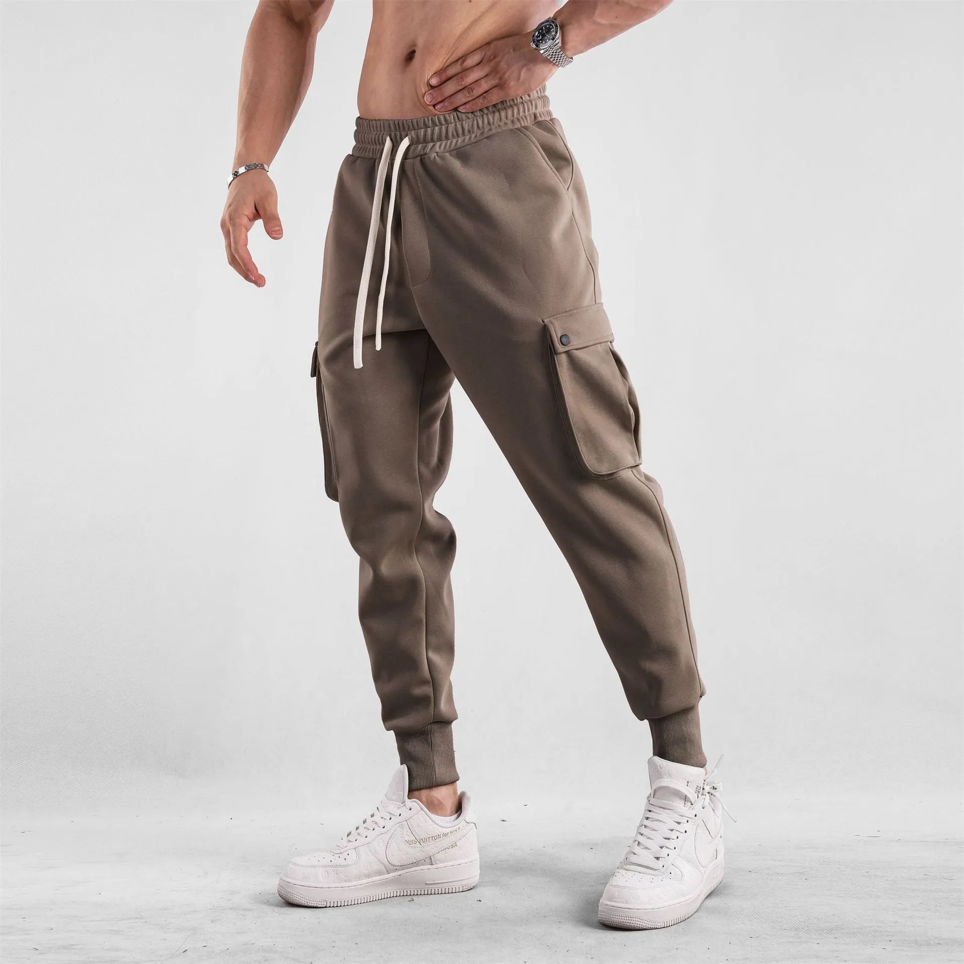 Men's loose fit cotton trousers with ankle-tied cuffs and multiple pockets in a light grey colour.