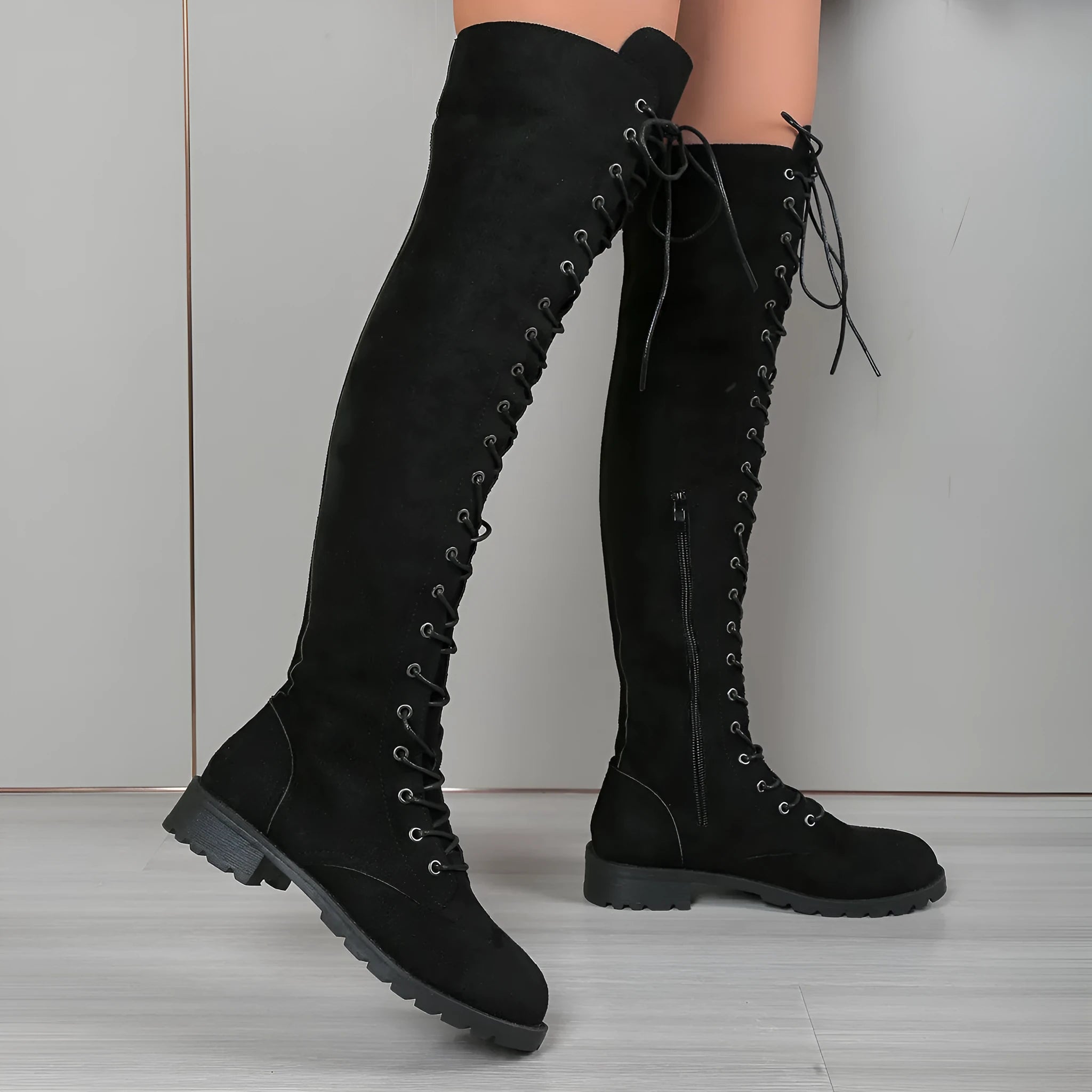 Women's black lace-up over-the-knee boots with flat heel and round toe on a neutral background