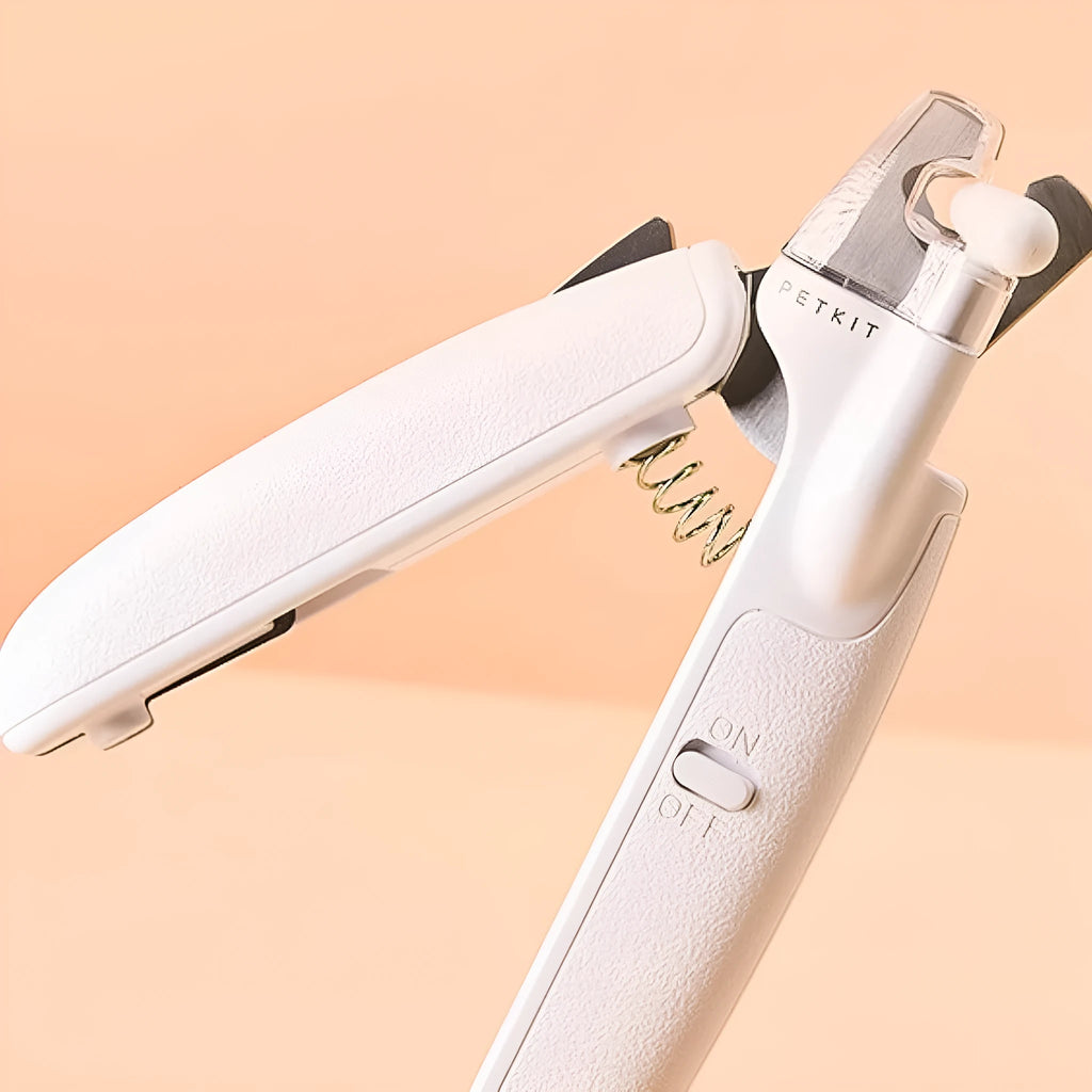 White pet nail clippers with LED light, anti-splash guard, and a nail file on a table.