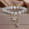 White cat's eye crystal bracelet with a silver flower tassel and safety buckle.
